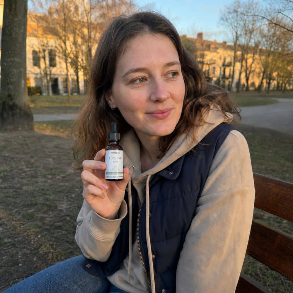 Donna che tiene in mano un flacone di olio di CBD Lucerne all'aperto in un parco